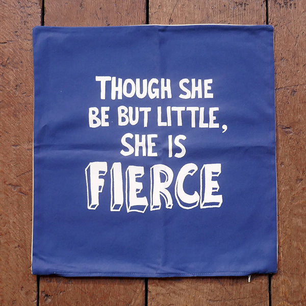 Royal blue cotton cushion cover with bold white graphic quote in centre front, lying on wooden panelling