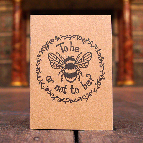 Pocket-sized notebook with a kraft card cover. The cover has a design adapted from a lino-print of a bumble bee and a quote from Shakespeare play, Hamlet (to be or not to be). The design is surrounded by a ring of leaves and flowers. The design is printed in black.
