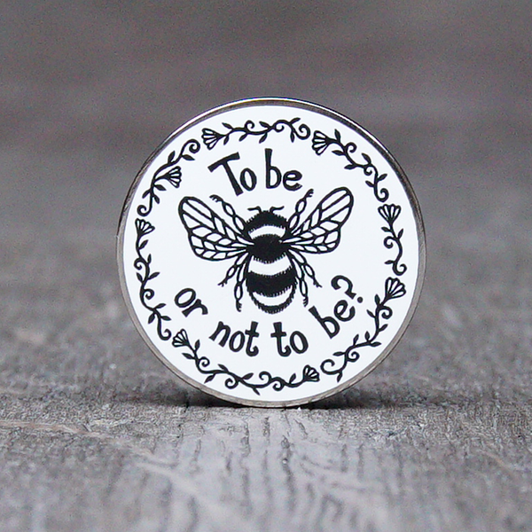 White circular pin badge with black graphic bee and text