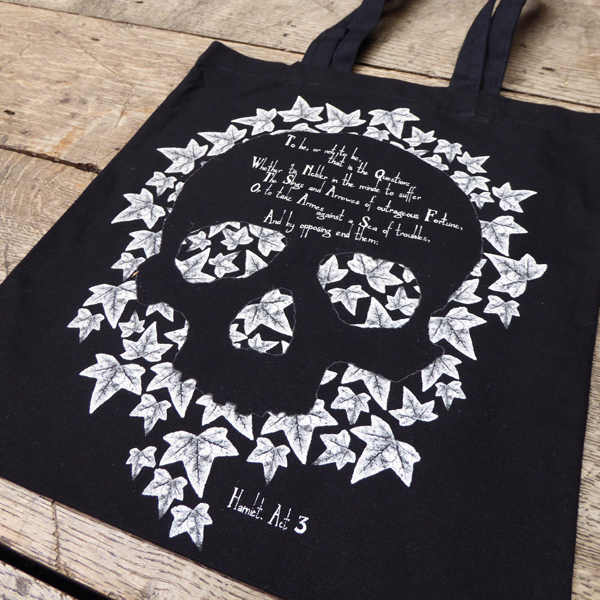 Black cotton tote bag with 2 handles and white leaf graphic of skull in centre