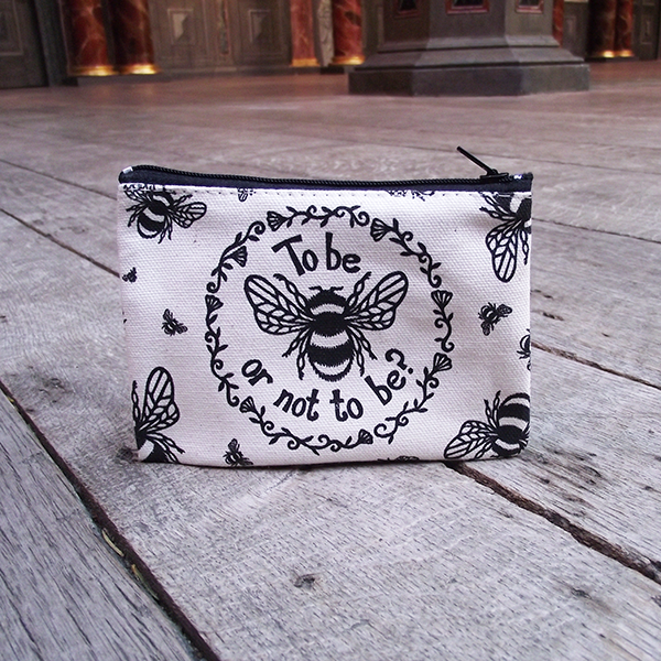 
                  
                    Rectangular purse made from unbleached cotton with a black zip closure. The purse is printed with a design adapted from an original print in black, a bumble bee and a quote from Shakespeare play, Hamlet (to be or not to be) is surrounded by a ring of flowers and leaves. Smaller bees surround the central image, flying in different directions.
                  
                