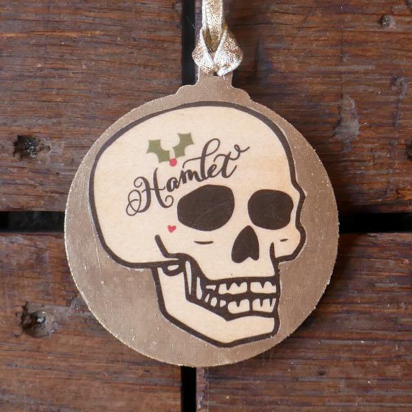 
                      
                        Round, flat, gold, Christmas decoration with Hamlet skull on it
                      
                    