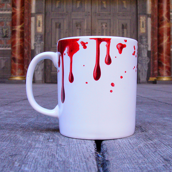 
                  
                    White earthenware coffee mug with a design of realistic red blood drips circling the rim and dripping down the mug. Inside the inner rim of the mug is a quote from Shakespeare play, Macbeth (Out, damned spot! Out, I say!) written in angry hand-drawn black letters. The O in the word spot is represented by a single drop of red blood.
                  
                