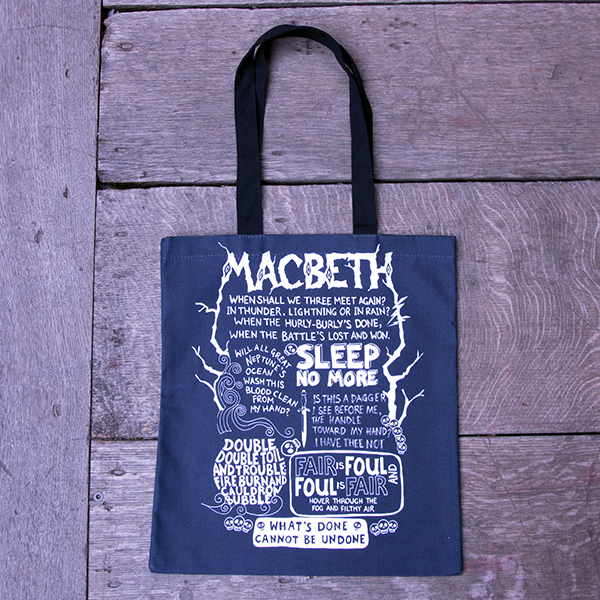 Black cotton bag with black mid-length handles, printed in white with all the best known quotes from Shakespeare play, Macbeth. The quotes are all formed of hand-drawn lettering in different styles. The name of the play is printed at the top in letters that mimic wood.