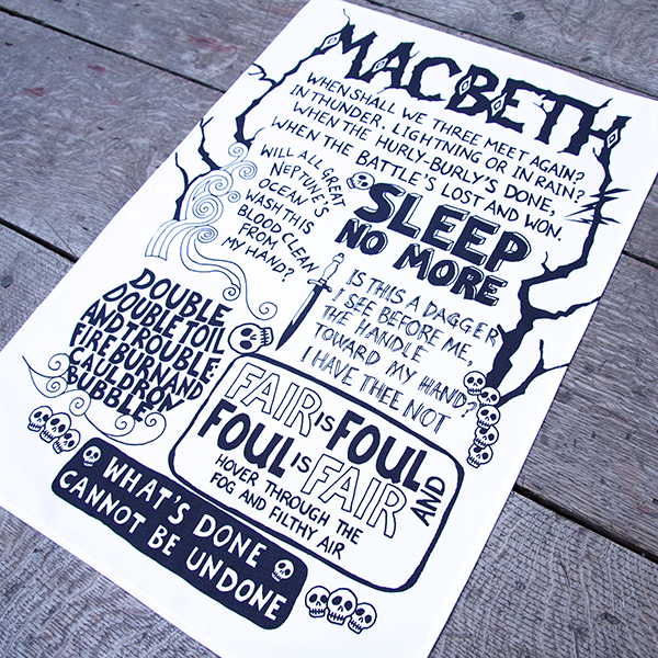 White cotton tea towel with a large chest print. The print is a montage of the best known quotes from Shakespeare play, Macbeth in black. The quotes are rendered in hand-drawn lettering in various styles. the name of the play is printed at the top of the design in capital letters made to look like wood.