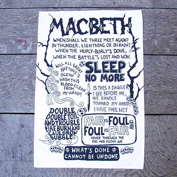 White cotton tea towel with a large chest print. The print is a montage of the best known quotes from Shakespeare play, Macbeth in black. The quotes are rendered in hand-drawn lettering in various styles. the name of the play is printed at the top of the design in capital letters made to look like wood.