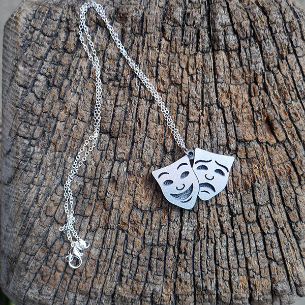 Comedy and Tragedy masks pendant made from silver sparkle acrylic on a silver chain.
