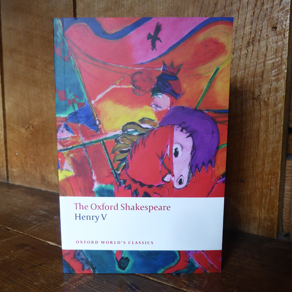 Pink, purple, orange, blue and yellow abstract depiction of a soldier on a decorated horse on this paperback book cover