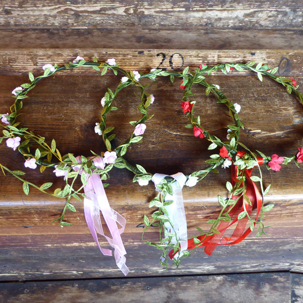 
                  
                    Wire and paper flower crowns. Wire wrapped in green paper leaves and a choice of red, pink or white paper flowers. Finished with matching ribbons. 
                  
                