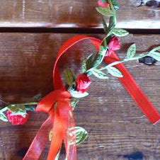 
                  
                    Wire and paper flower crown. Wire wrapped in green paper leaves and red  paper flowers. Finished with matching ribbon. 
                  
                