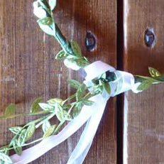 
                  
                    Wire and paper flower crown. Wire wrapped in green paper leaves and white paper flowers. Finished with matching ribbon. 
                  
                