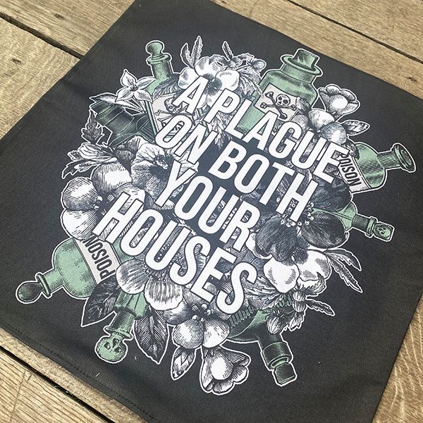 Black cotton cushion cover, printed with an image image celebrating Shakespeare play, Romeo & Juliet. A background of black and white flowers and green poison bottles with a quote fro the play, "a plague on both you house" printed in white capital letters.