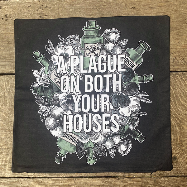 Black cotton cushion cover, printed with an image image celebrating Shakespeare play, Romeo & Juliet. A background of black and white flowers and green poison bottles with a quote fro the play, 