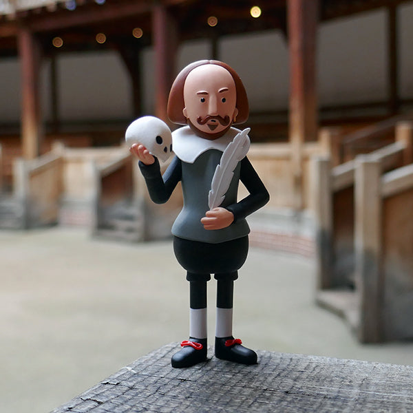 Figure of William Shakespeare made from eco PVC. Shakespeare stands 10 cm high, he is wearing a grey jerkin, black pants, and a white ruff. He is holding a white human skull and a white quill pen.
