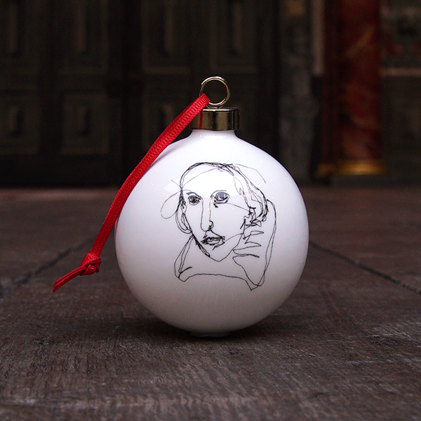 White fine china hanging bauble with a gold ferule and red ribbon. On the bauble is a portrait of William Shakespeare based on an embroidery. The portrait is made up of black lines and has a scribbled look.