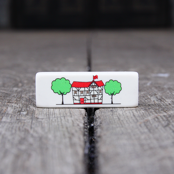 White rectangular eraser printed with a cartoon of the Globe Theatre. The cartton shows the theatre with its wooden frame and red roof, flag and door. The theatre is flanked by two green trees