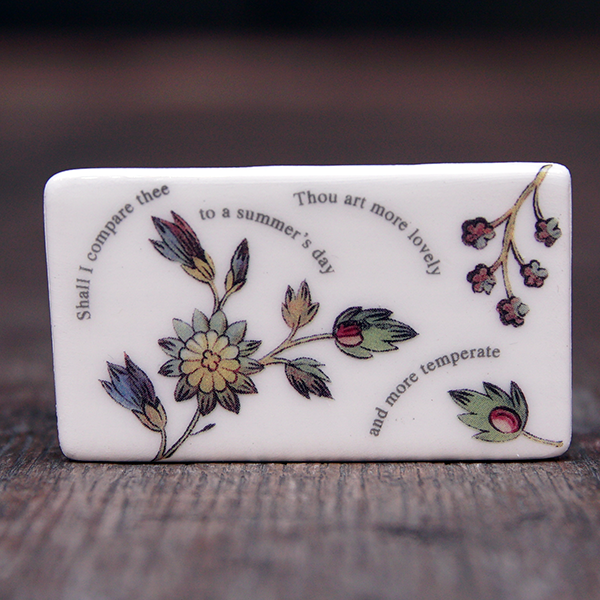 
                  
                    Rectangular ceramic brooch with lines from Shakespeare's Sonnet 18 and images of flowers
                  
                