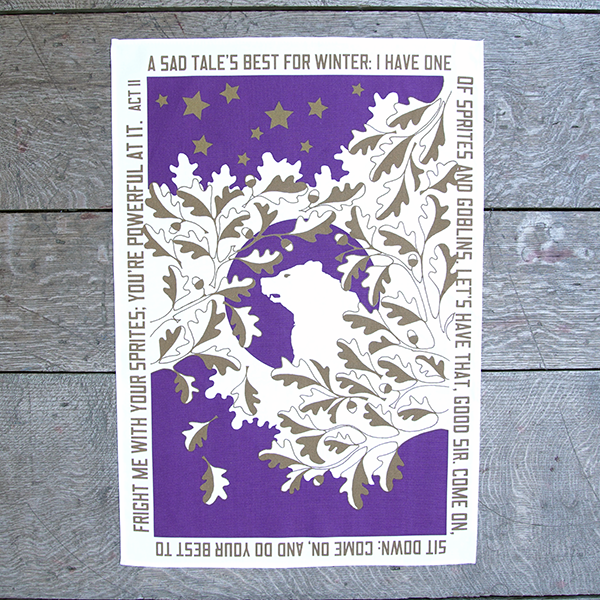 White cotton tea towel with a print celebrating Shakespeare play, The Winter's Tale. The print is portrait orientation. A rich purple rectangle is bisected by a flurry of gold and white oak leaves. In the centre of the leaves is a white bear in profile. Around the edges of the rectangle a quote from the play is printed in gold letters, 