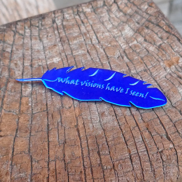 Feather shaped brooch made from mirror blue perspex.. The feather is engraved with a quote from Shakespeare play, A Midsummer Night's Dream, "what visions have I seen!"
