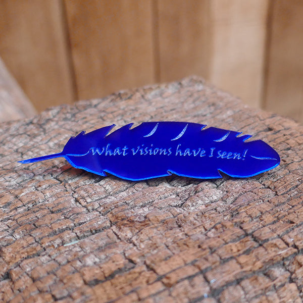 Feather shaped brooch made from mirror blue perspex.. The feather is engraved with a quote from Shakespeare play, A Midsummer Night's Dream, "what visions have I seen!"