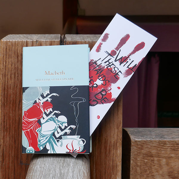 
                      
                        Large white card bookmark with an image of a bloody handprint. Over the hand print is a quote from Shakespeare play, Macbeth, printed in black hand-drawn lettering. Shown with a copy of the Collector's Library 'Macbeth'
                      
                    