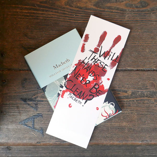 Large white card bookmark with an image of a bloody handprint. Over the hand print is a quote from Shakespeare play, Macbeth, printed in black hand-drawn lettering. Shown with a copy of the Collector's Library 'Macbeth'